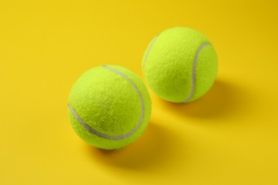 Photo of Two bright tennis balls on yellow background