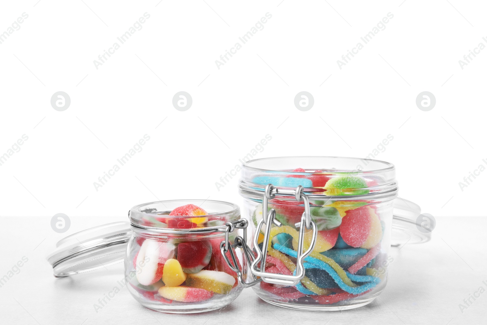 Photo of Tasty jelly candies in jars on light grey table