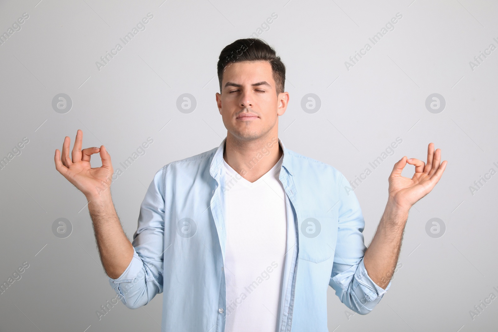 Photo of Man meditating on light background. Stress relief exercise