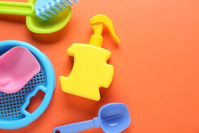 Photo of Bottle of suntan cream and children's beach toys on orange background, flat lay. Space for text