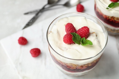 Photo of Delicious oatmeal dessert with raspberries in glass on marble board