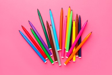 Many bright markers on pink background, flat lay