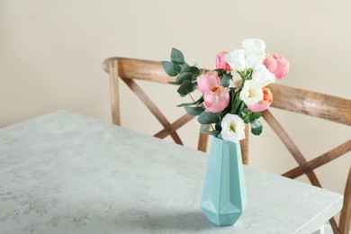 Vase with beautiful flowers as element of interior design on table in room. Space for text