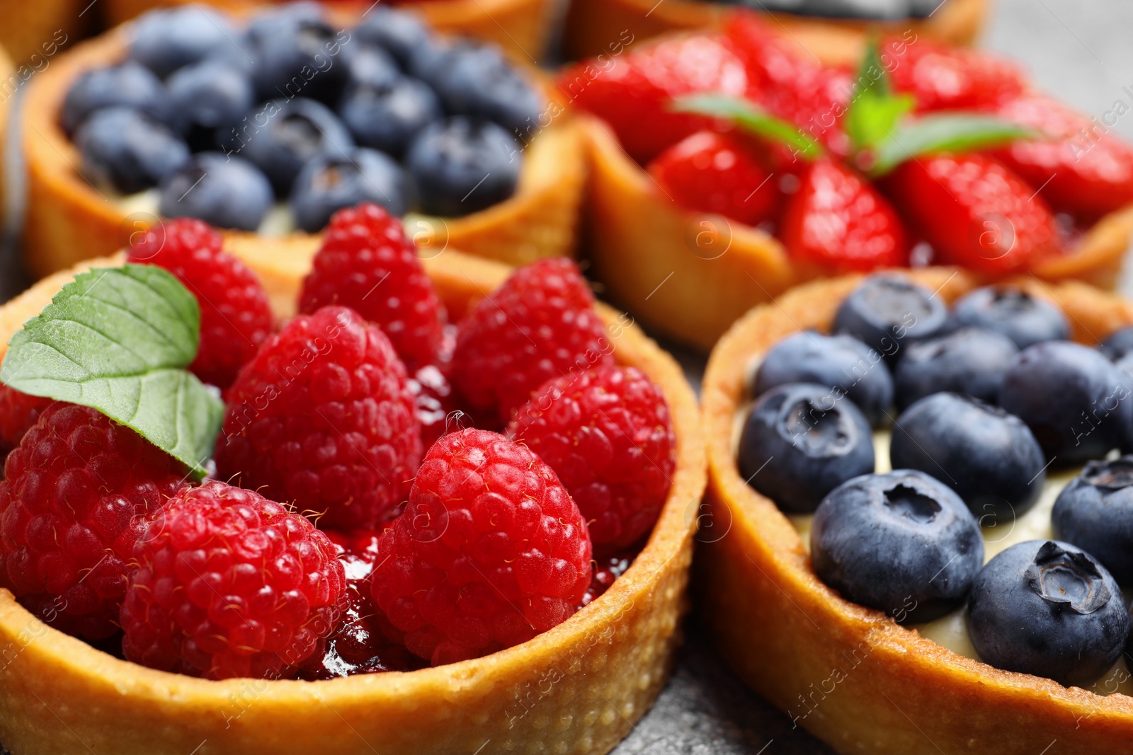 Photo of Tartlets with different fresh berries on table, closeup. Delicious dessert