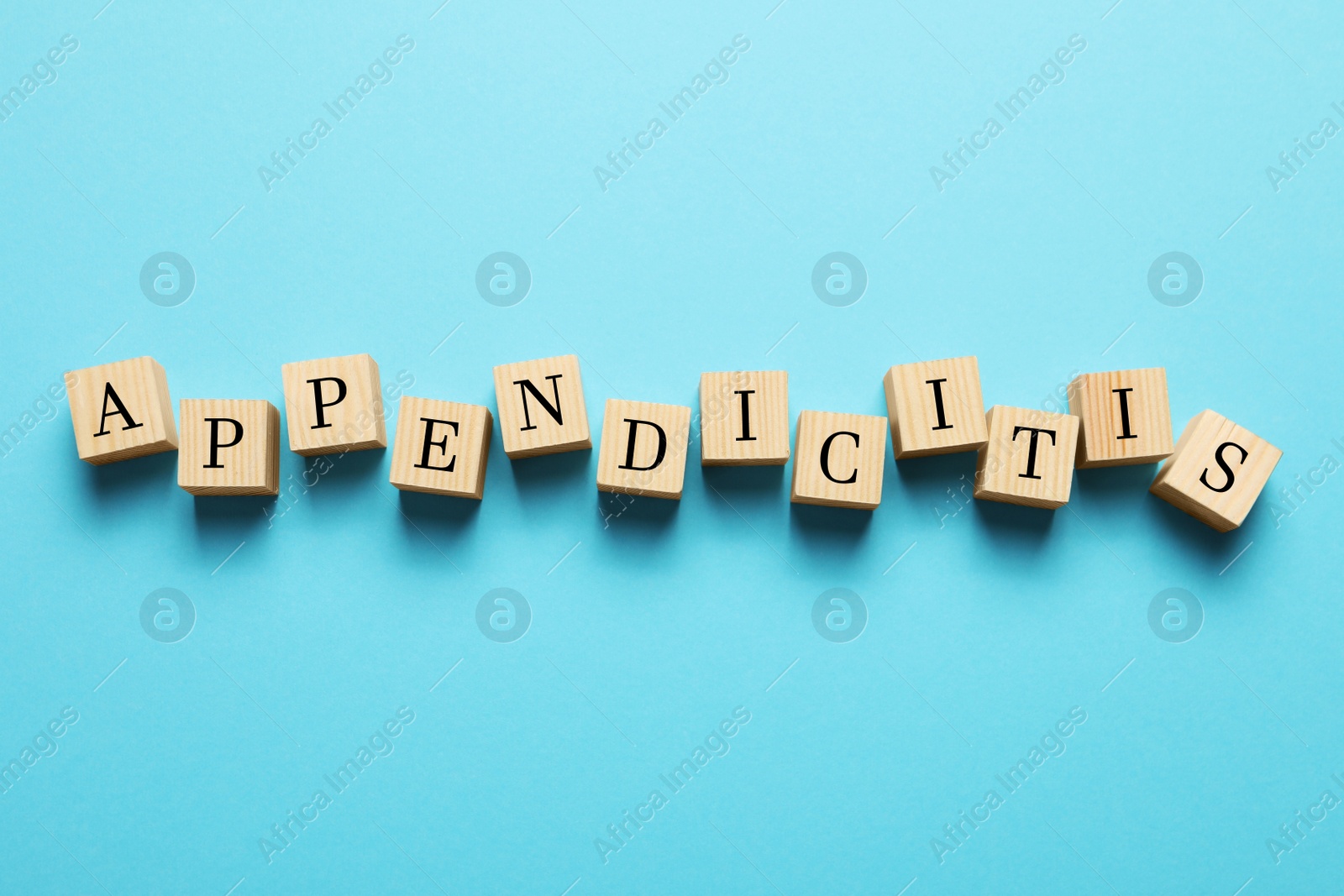 Photo of Word Appendicitis made of wooden cubes with letters on light blue background, top view