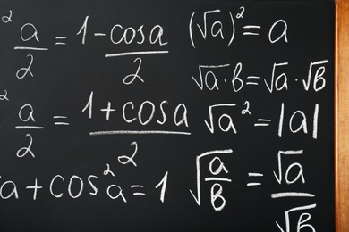 Photo of Different mathematical formulas written with chalk on blackboard