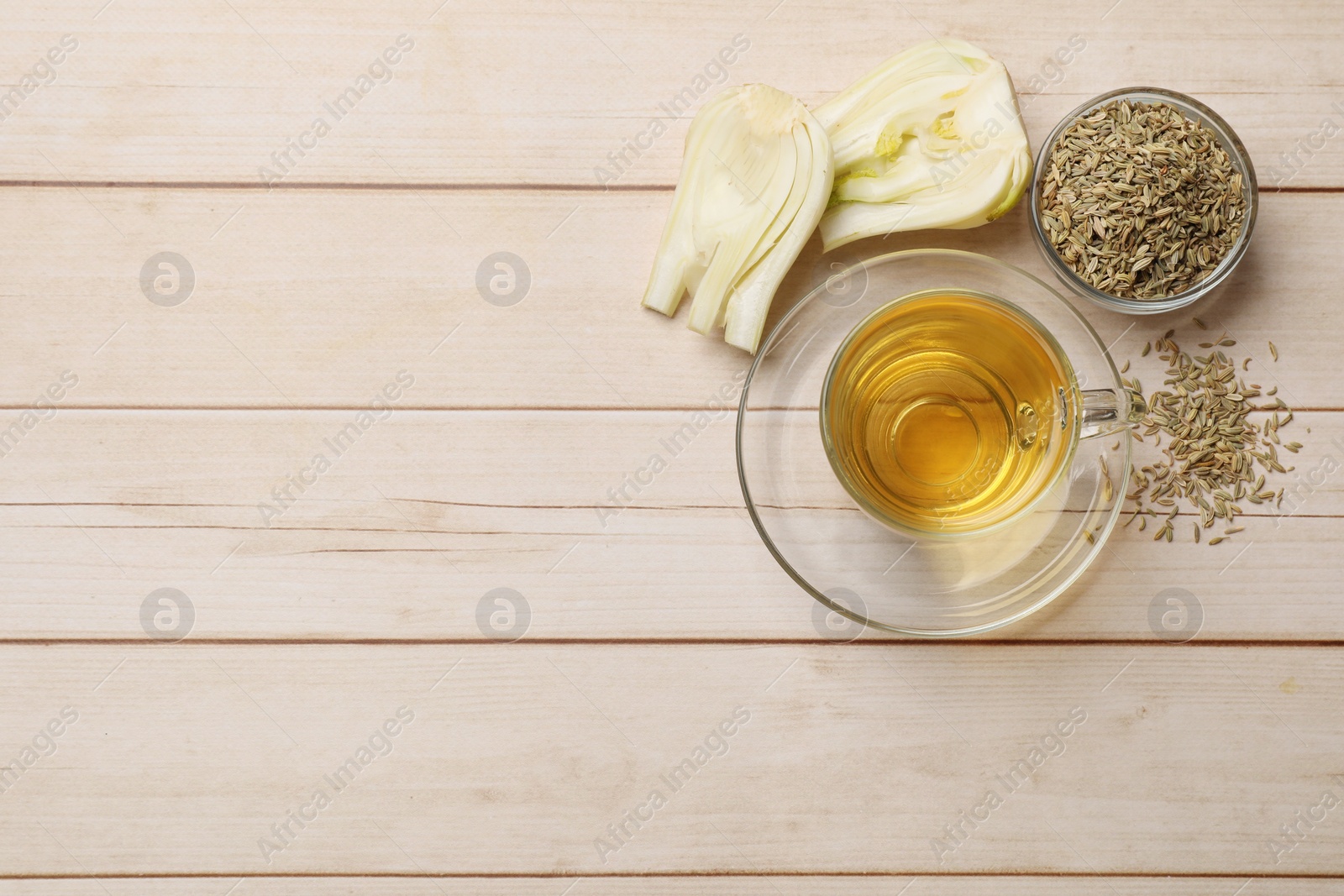 Photo of Aromatic fennel tea, seeds and fresh vegetable on wooden table, flat lay. Space for text