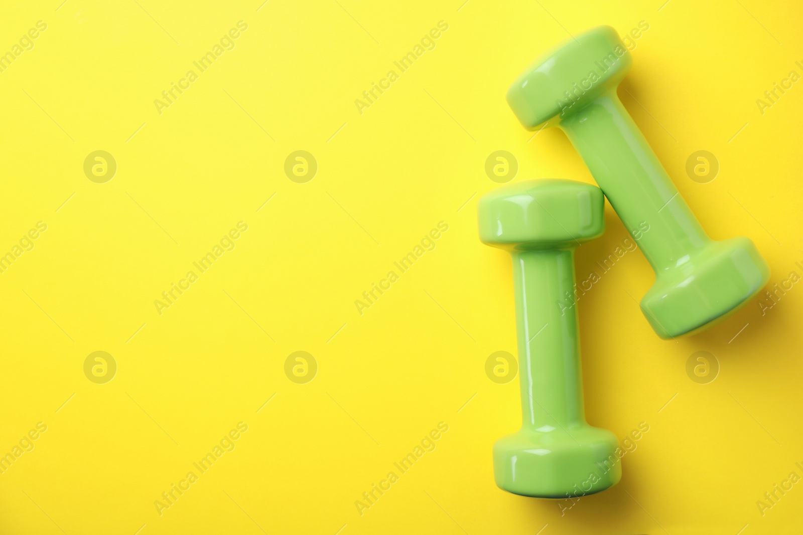 Photo of Bright dumbbells and space for text on color background, flat lay. Home fitness