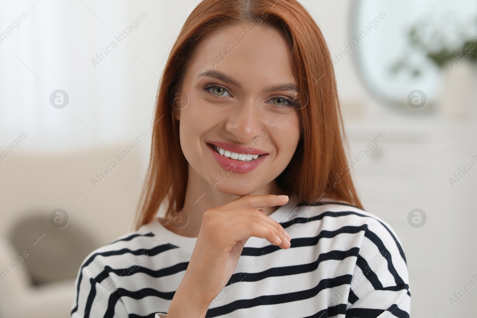 Photo of Portrait of beautiful young woman with red hair at home. Attractive lady smiling and looking into camera