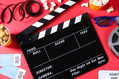 Flat lay composition with clapperboard and popcorn on red background