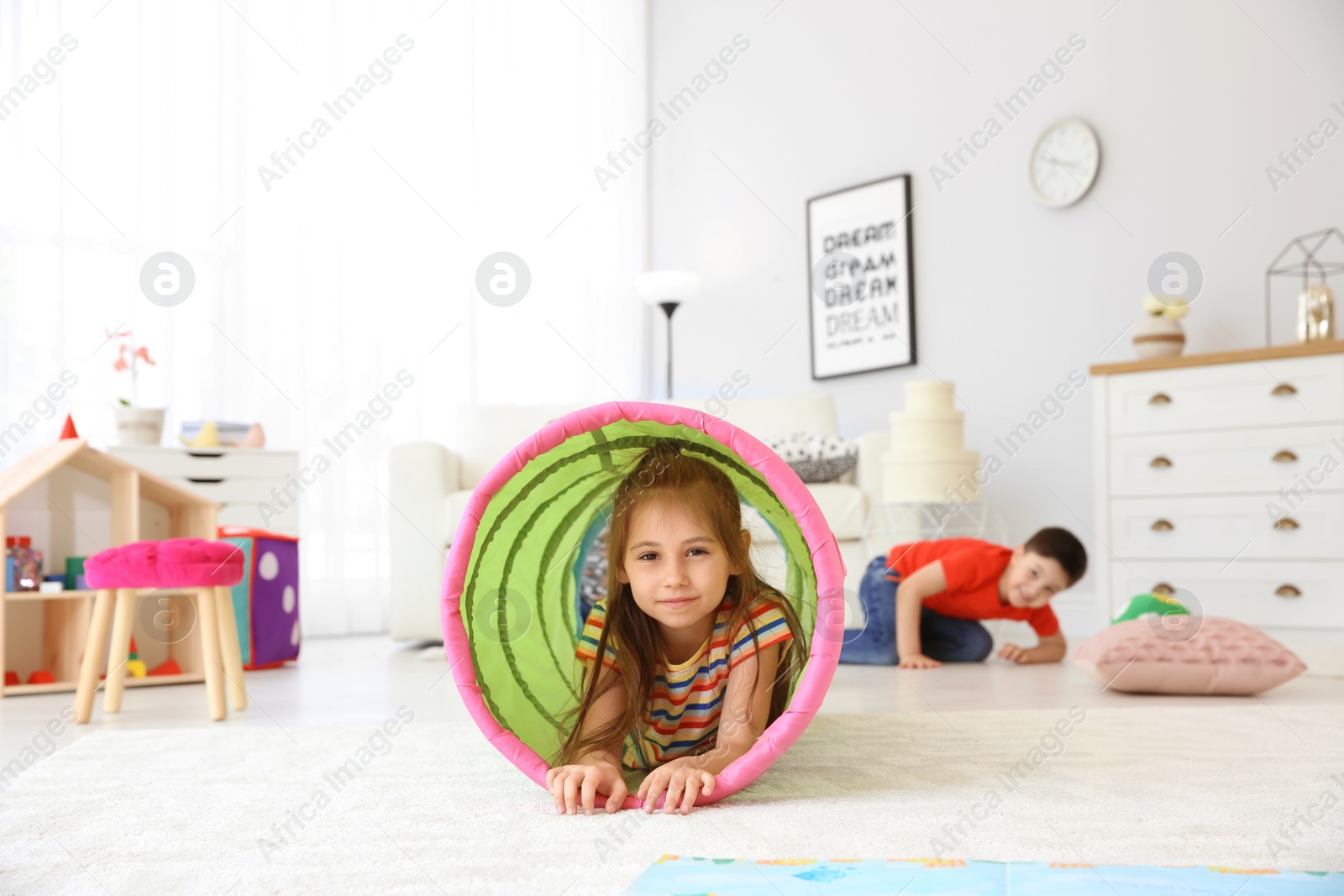 Photo of Cute little child in playing tunnel on floor, indoors