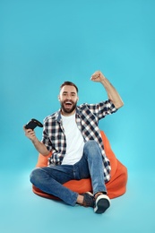 Emotional young man playing video games with controller on color background. Space for text
