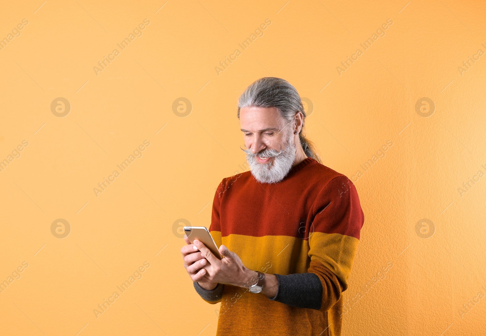 Photo of Portrait of handsome mature man with mobile phone on color background