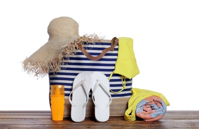 Photo of Stylish bag, sunscreen and other beach accessories on wooden table against white background