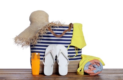 Stylish bag, sunscreen and other beach accessories on wooden table against white background