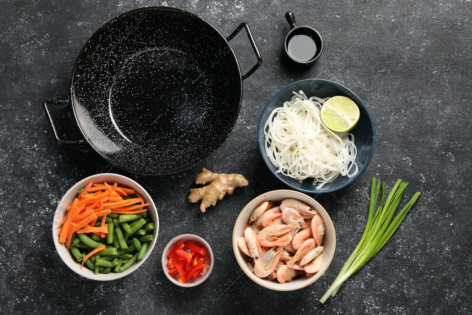 Photo of Flat lay composition with black wok and products on dark textured table