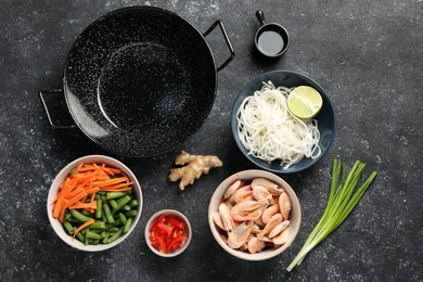 Flat lay composition with black wok and products on dark textured table