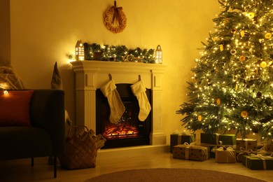 Stylish fireplace near decorated Christmas tree and accessories in cosy room