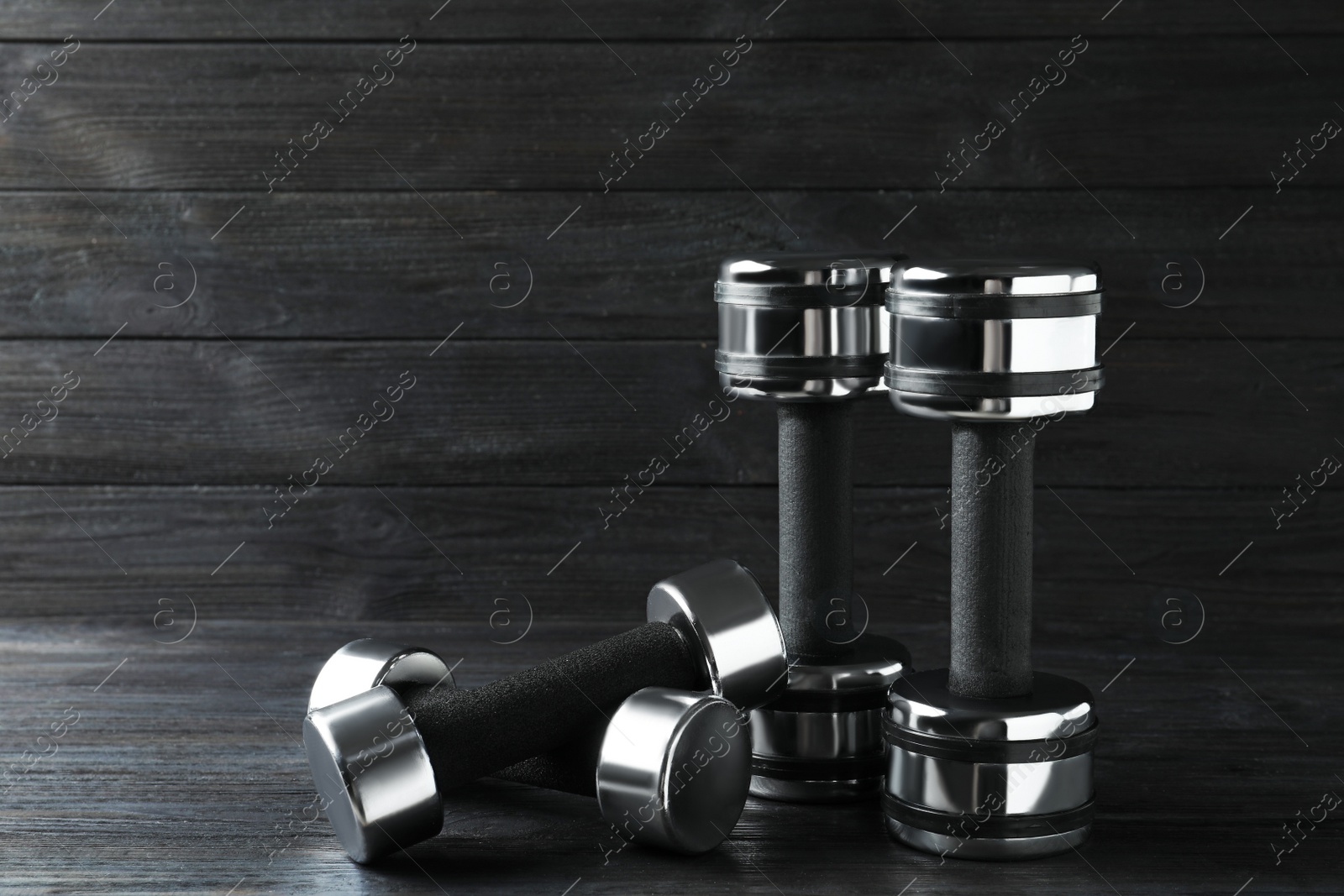 Photo of Set of metal dumbbells on black wooden table