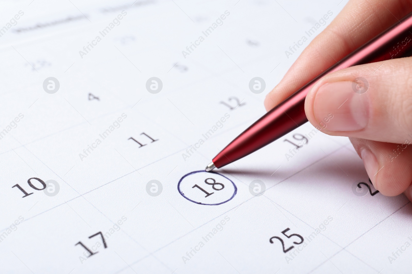 Photo of Woman marking date in calendar with pen, closeup