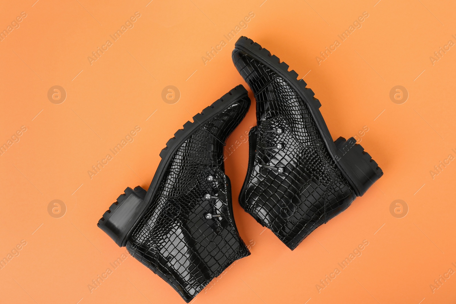 Photo of Pair of stylish ankle boots on orange background, top view