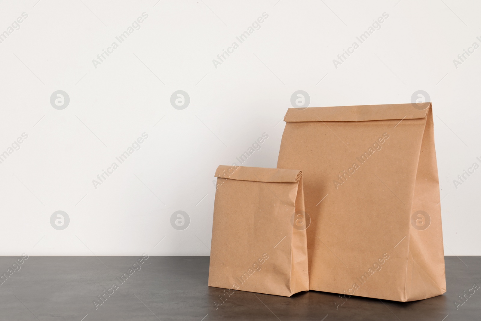 Photo of Paper bags on table against white wall. Mockup for design