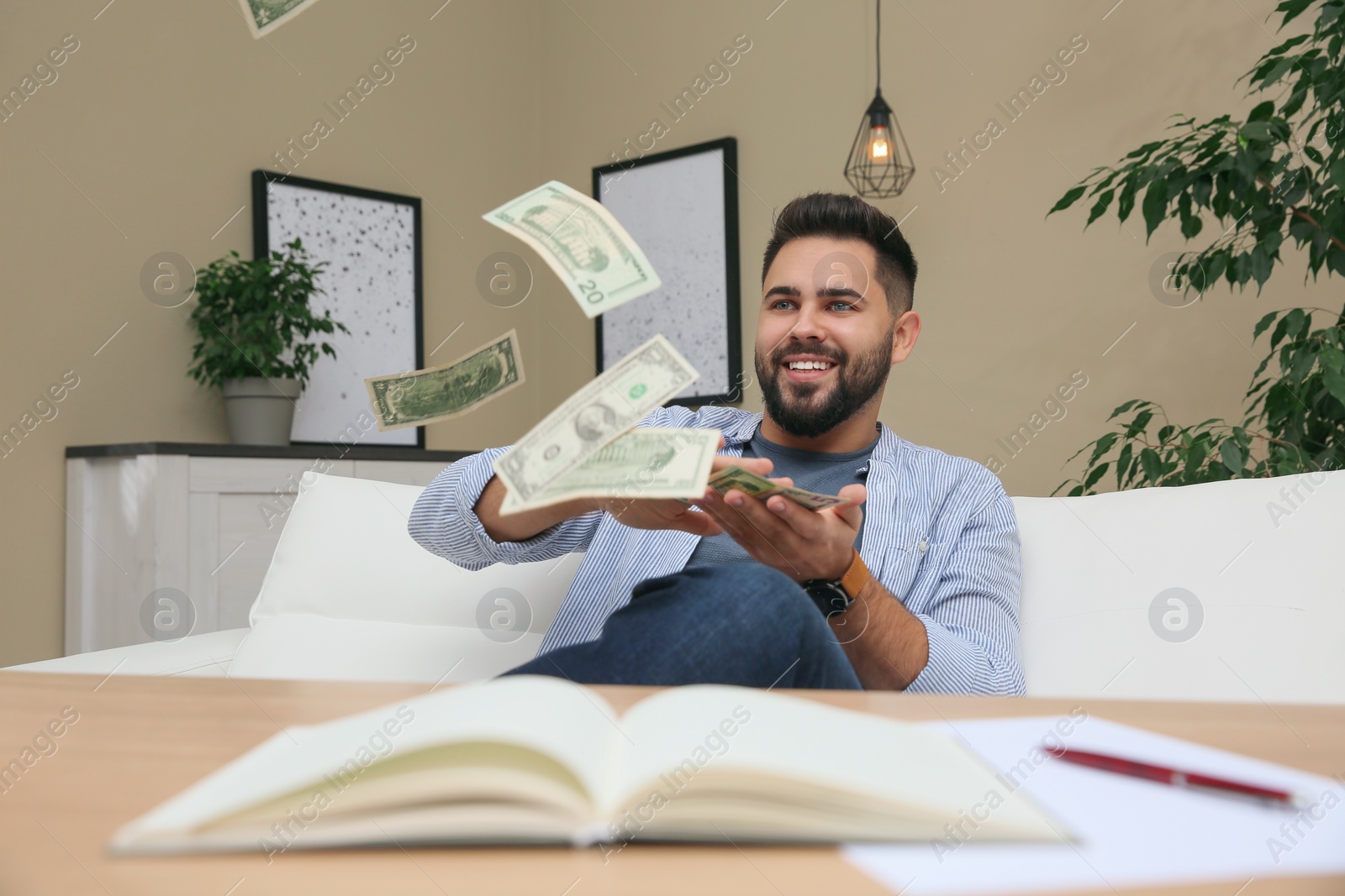 Photo of Young man throwing money at table indoors