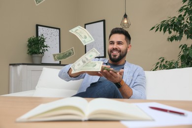 Young man throwing money at table indoors