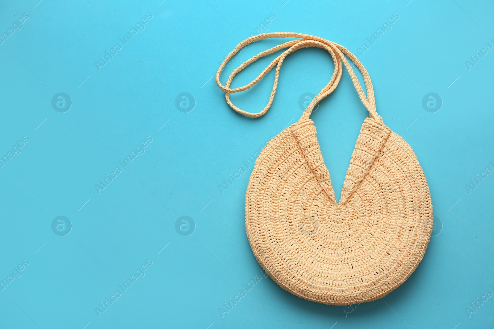 Photo of Elegant woman's straw bag on light blue background, top view. Space for text