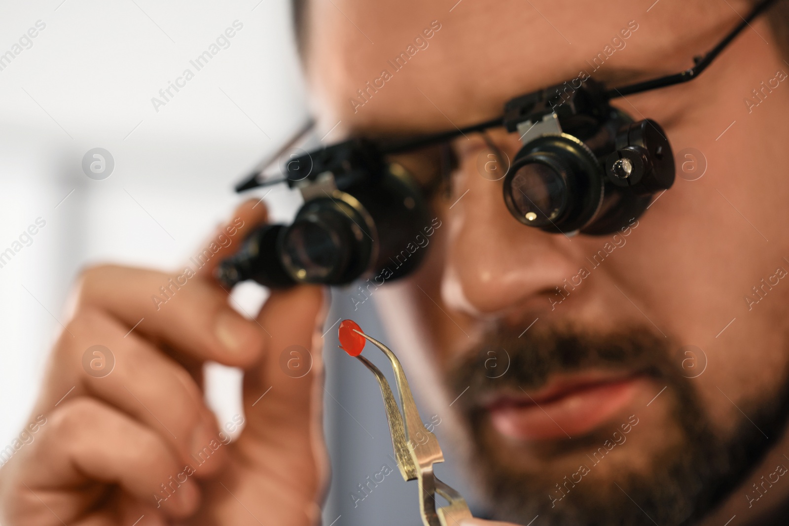 Photo of Jeweler working with gemstone on blurred background, closeup