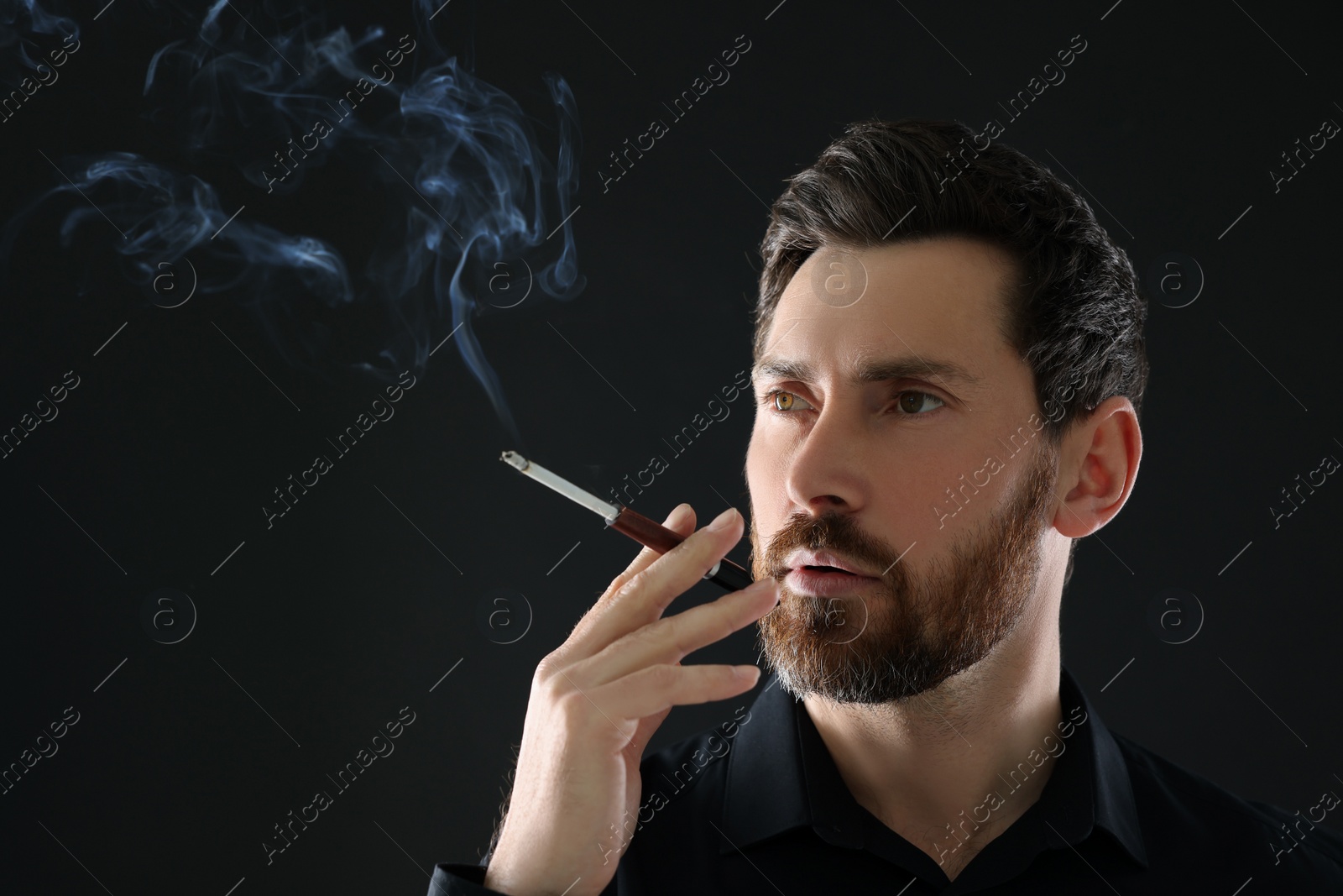 Photo of Man using cigarette holder for smoking on black background, space for text