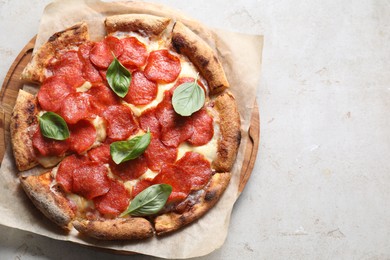 Tasty pepperoni pizza with basil on light grey table, top view. Space for text