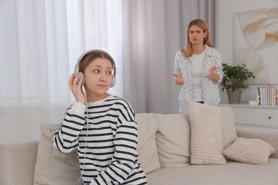 Teenage daughter with headphones ignoring her mother at home