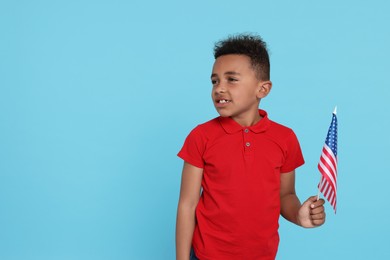 Photo of 4th of July - Independence Day of USA. Happy boy with American flag on light blue background, space for text