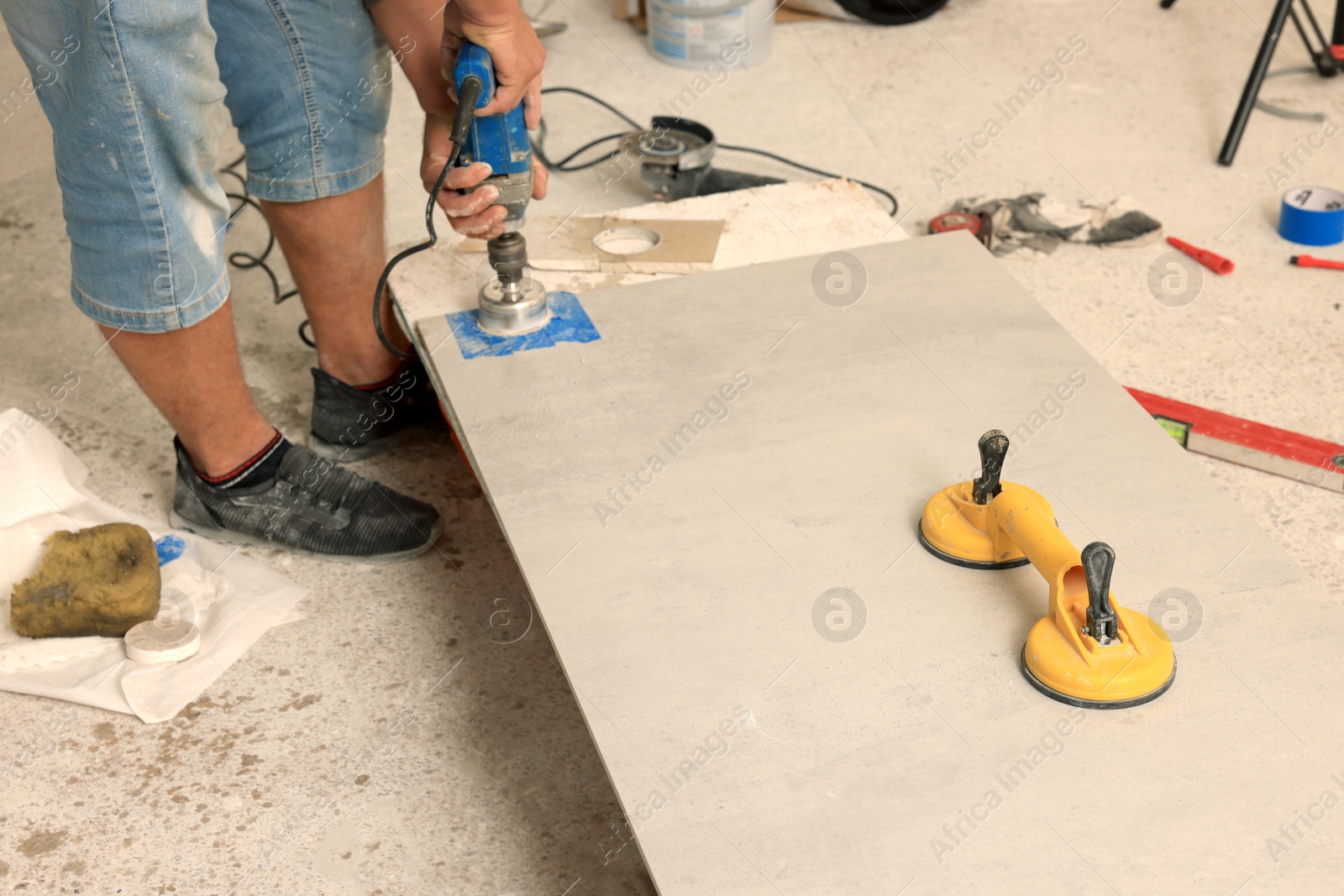 Photo of Worker making socket hole in tile indoors, closeup