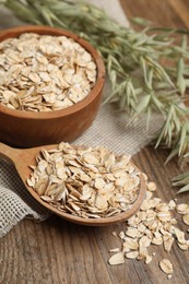 Photo of Bowl, spoon with oatmeal and florets on wooden table, closeup