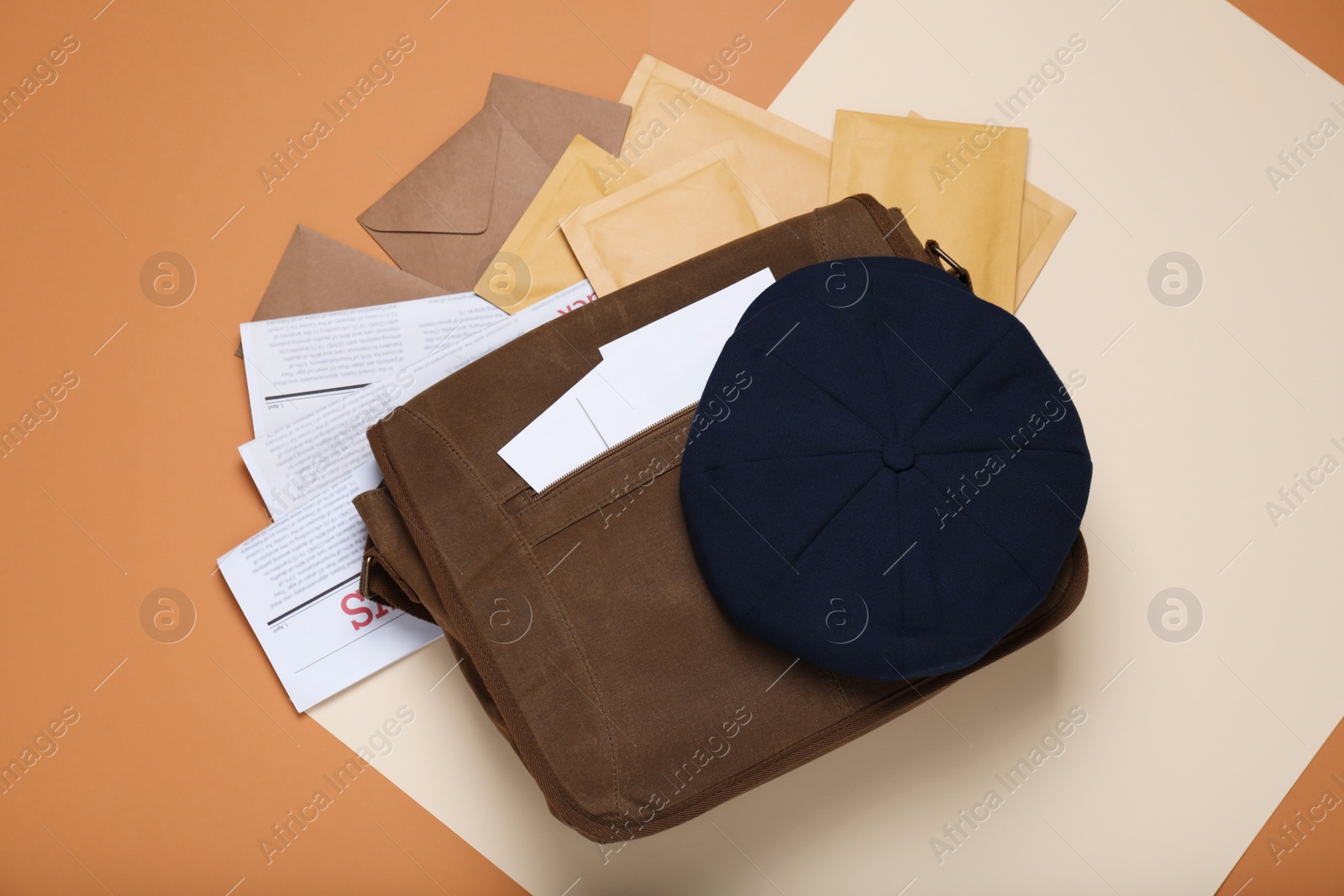 Photo of Postman bag, newspapers, mails and hat on color background, flat lay