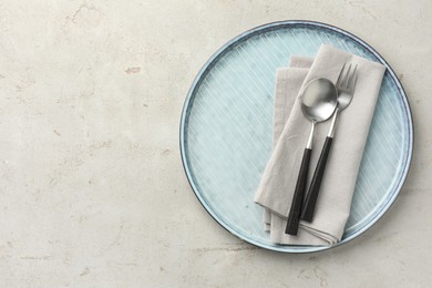 Photo of Stylish setting with cutlery, napkin and plate on light grey table, top view. Space for text