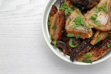 Tasty fried cracklings with parsley on white wooden table, top view and space for text. Cooked pork lard