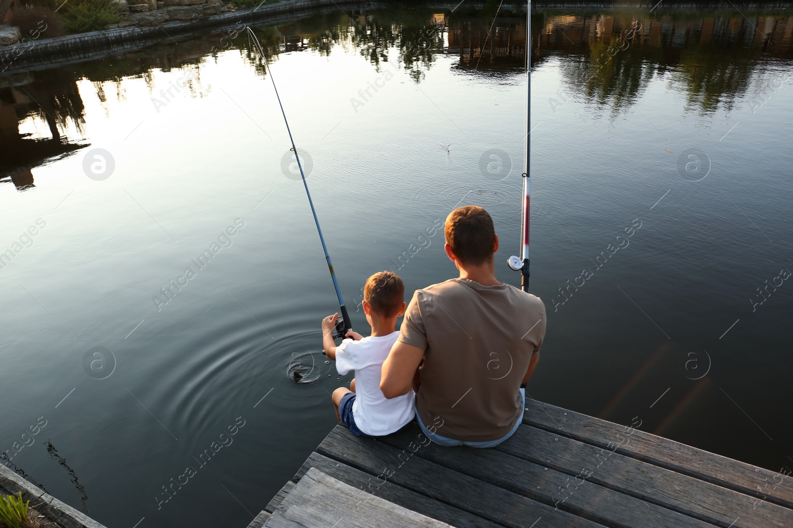 Photo of Dad and son fishing together on sunny day