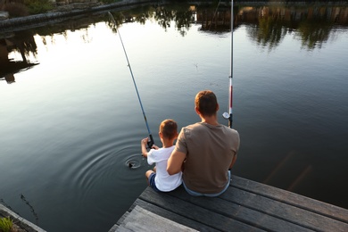 Photo of Dad and son fishing together on sunny day