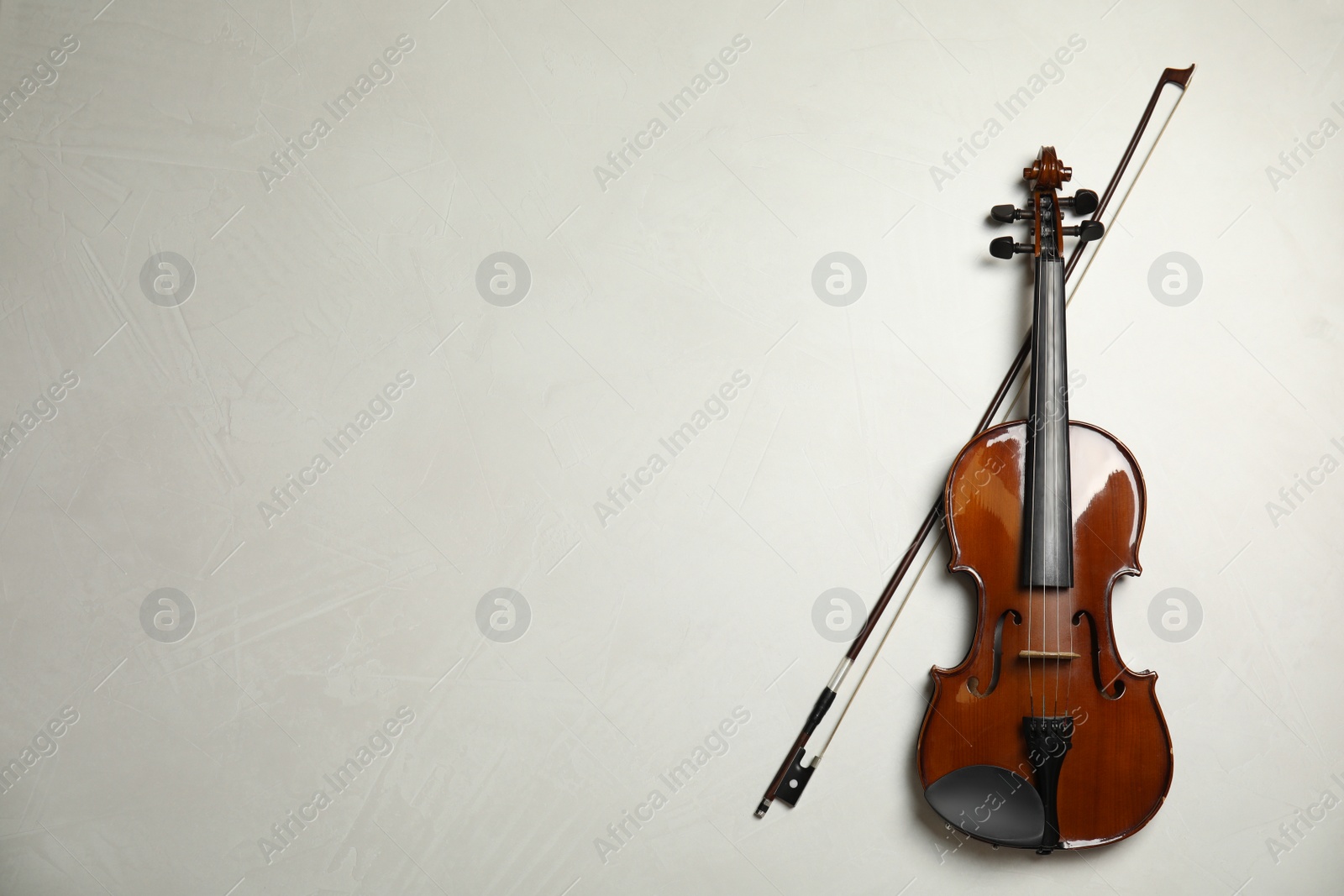 Photo of Beautiful violin and bow on grey stone table, flat lay. Space for text
