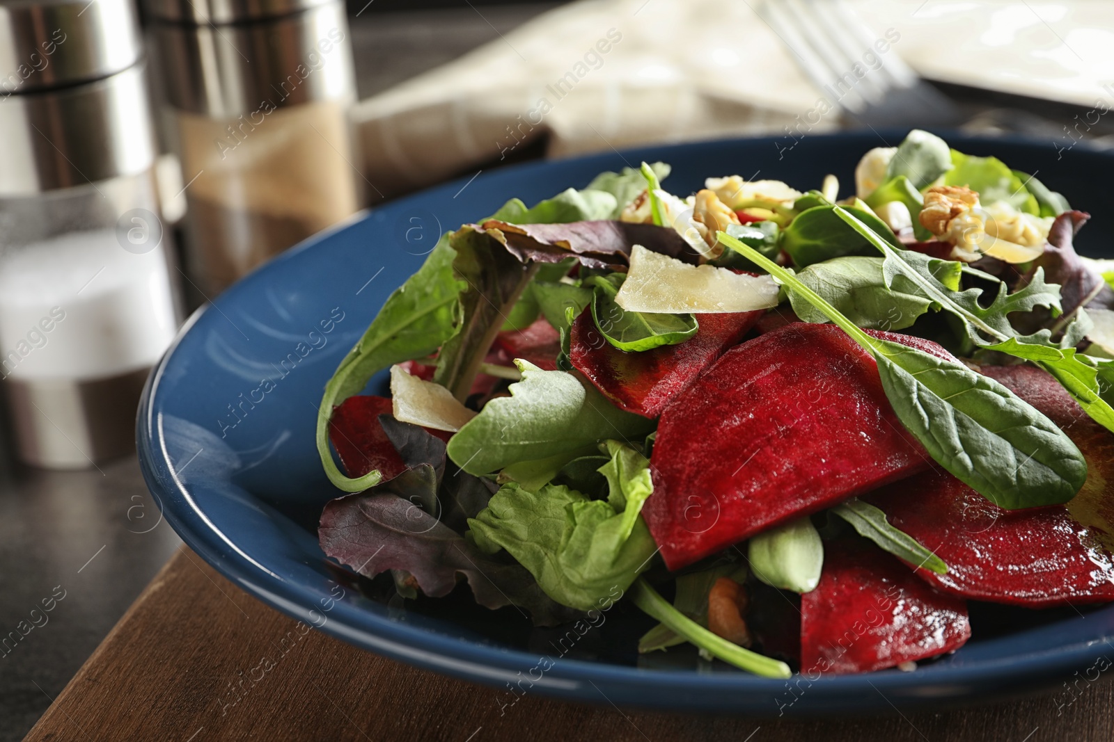 Photo of Plate with delicious beet salad on wooden board, closeup