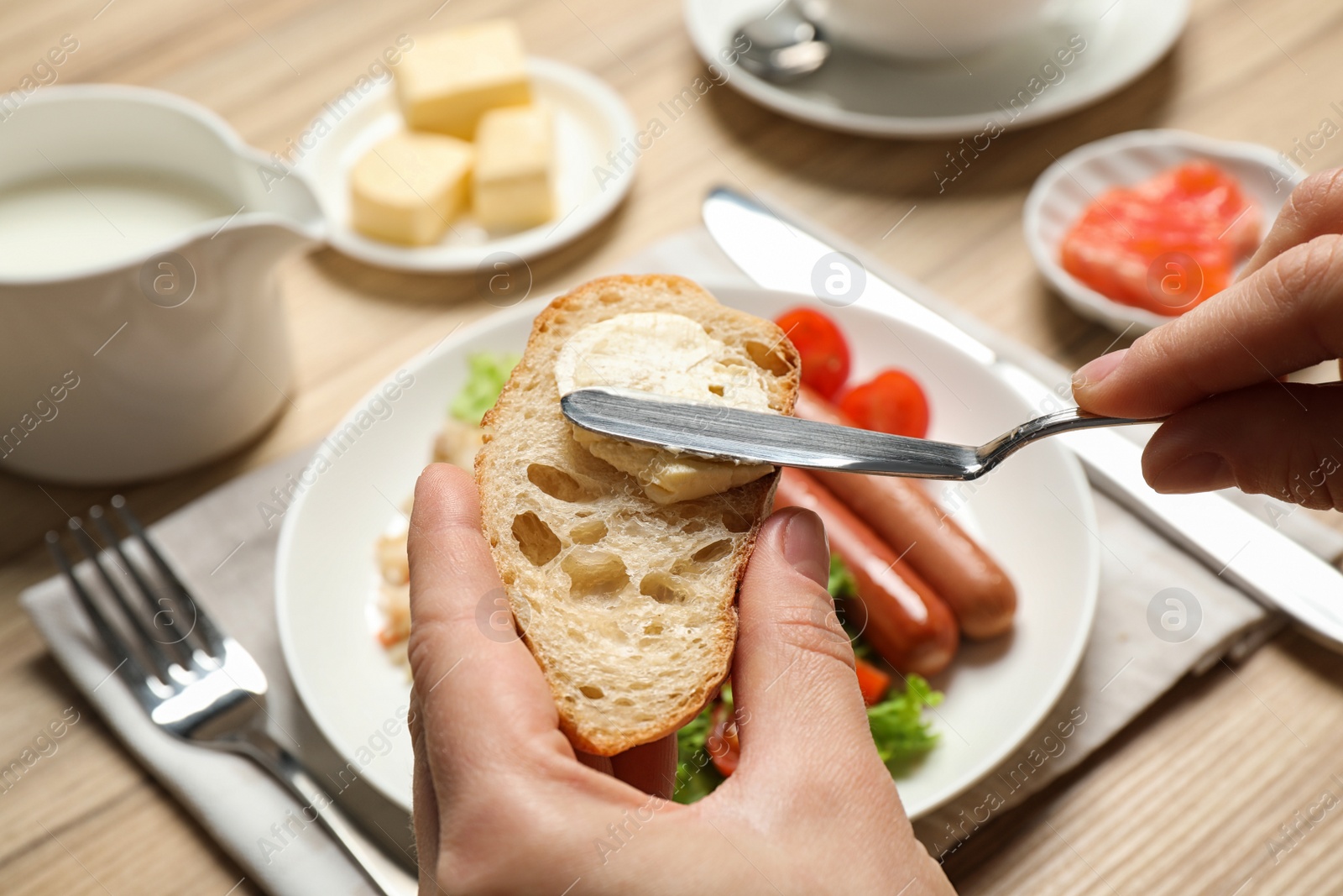 Photo of Woman spreading butter on toast at table, closeup. Buffet service