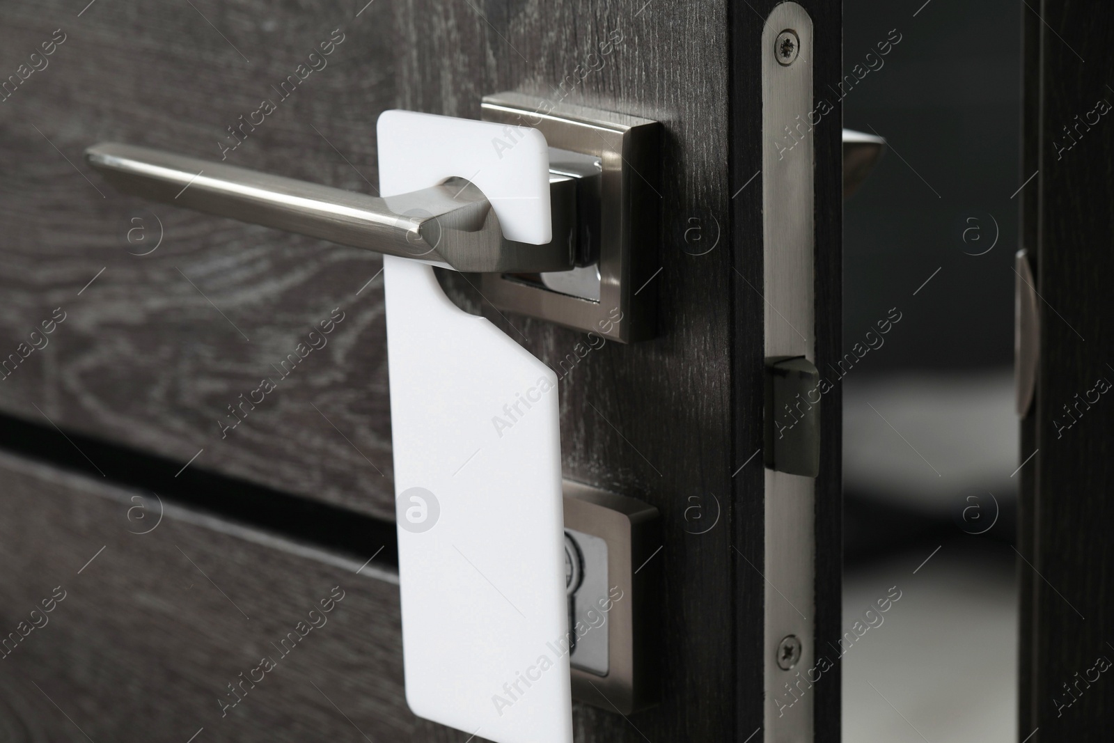 Photo of Wooden door with blank hanger on metal handle, closeup