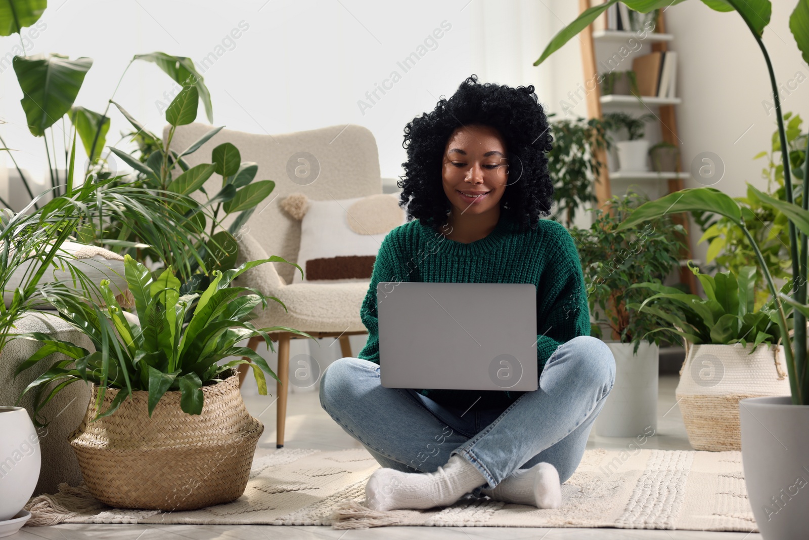 Photo of Relaxing atmosphere. Woman with laptop surrounded by potted houseplants in room