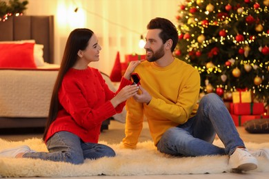 Man with engagement ring making proposal to his girlfriend at home on Christmas