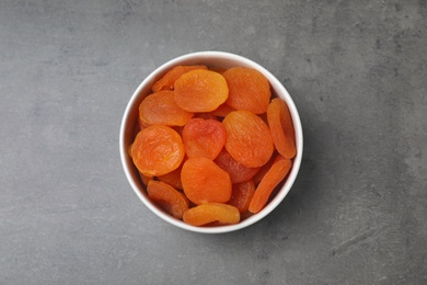 Bowl with dried apricots on grey background, top view. Healthy fruit