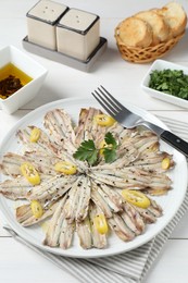 Photo of Tasty pickled anchovies served on white wooden table