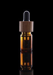 Photo of One brown bottle with tincture on mirror surface against black background